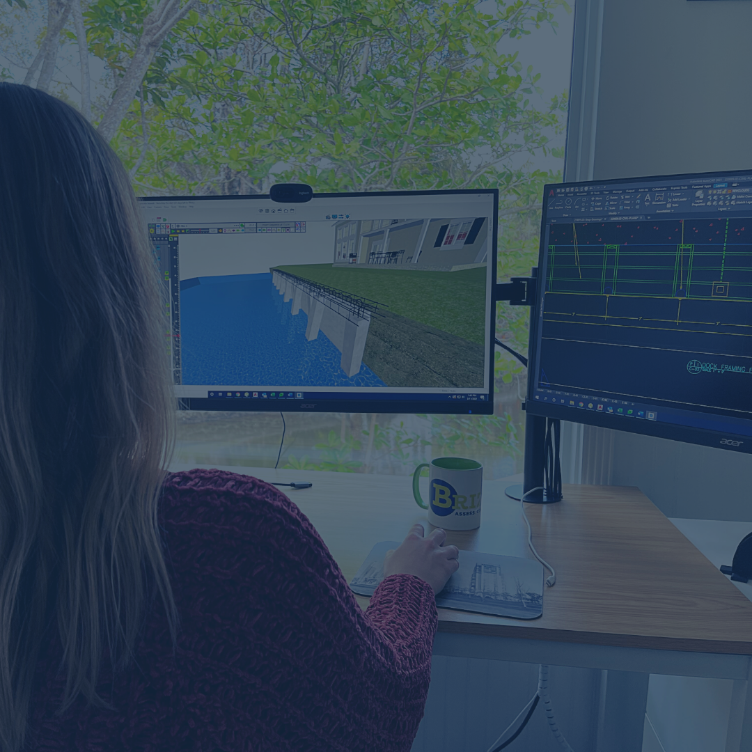 Photo of female staff member reviewing a seawall design on a computer.